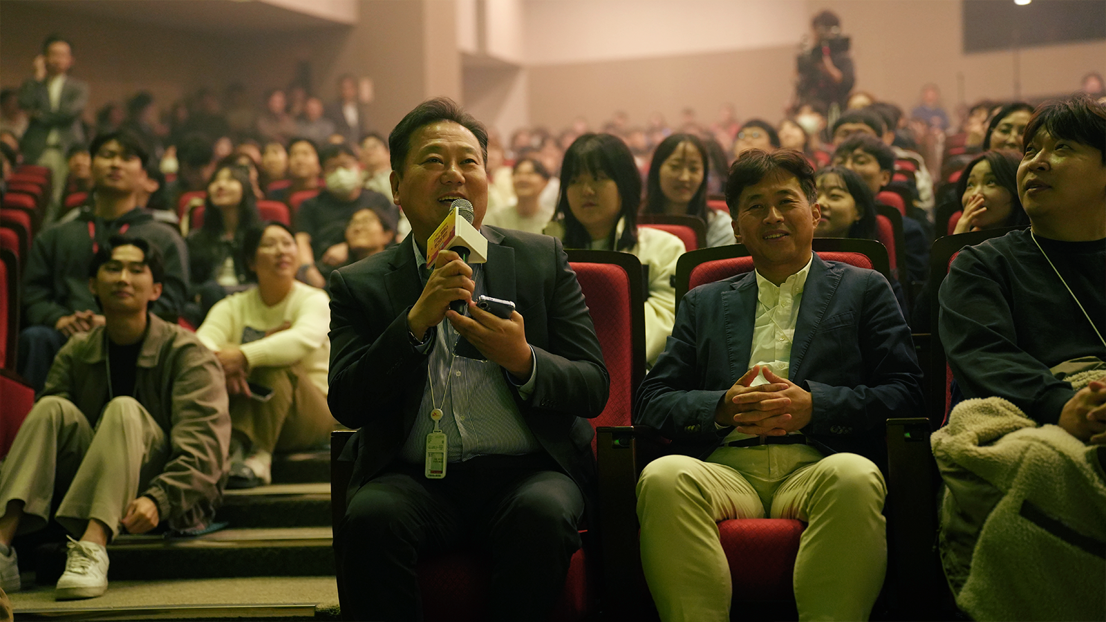 가수 거미가 무대에서 구성원들의 사연을 읽으며, 구성원들과 화기애애하게 대화를 나누고 있다.